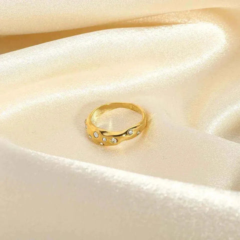 Gold snake-shape ring with zircon stones on cream satin background.