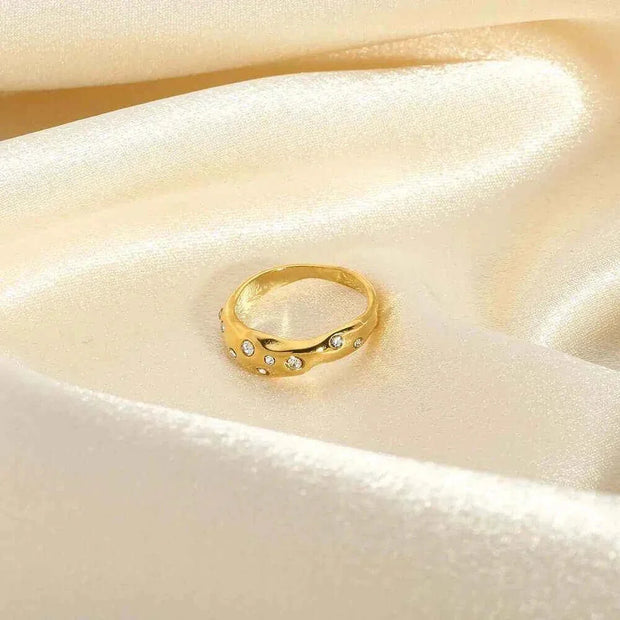 Gold snake-shape ring with zircon stones on cream satin background.