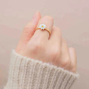 Hand wearing a daisy-designed Fidget Spinner Ring on a beige sweater background.