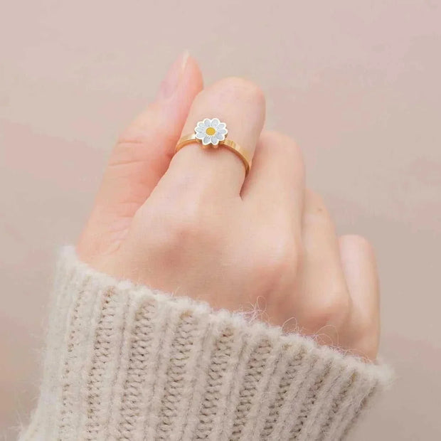 Hand wearing a daisy-designed Fidget Spinner Ring on a beige sweater background.