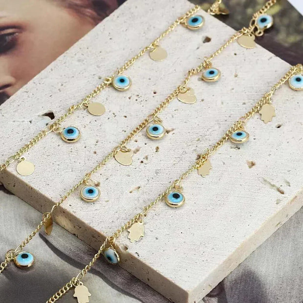 Gold charm bracelets with blue eye charms and round gold accents on a display board.