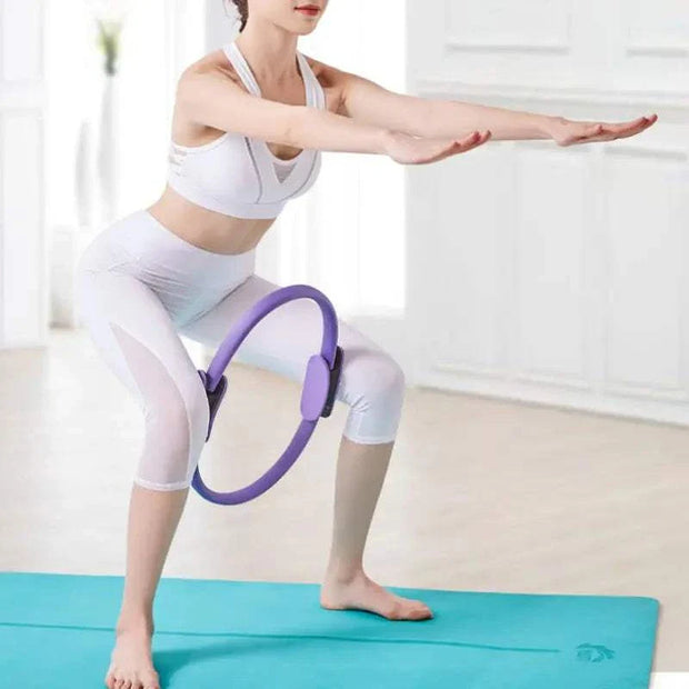 Woman using a purple Yoga Exercise Fitness Ring on a blue mat indoors.