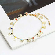 Elegant charm bracelet with colorful beads and gold chain on a book.