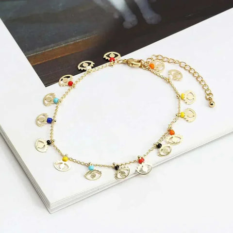 Elegant charm bracelet with colorful beads and gold chain on a book.