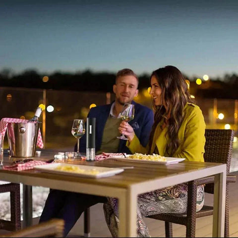 Couple enjoying wine on patio with automatic wine bottle opener.