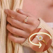 Gold fidget spinner ring with a daisy design, worn on a hand, highlighting the spinning feature.