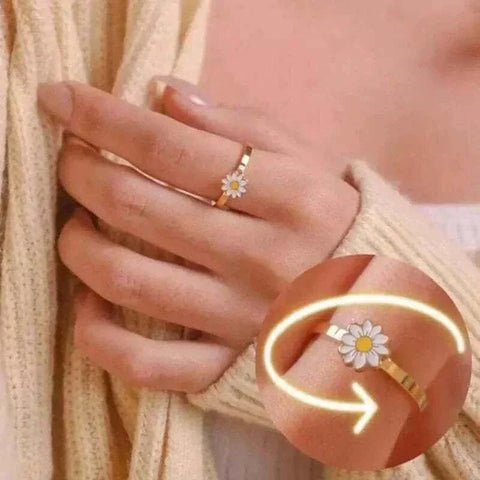 Gold fidget spinner ring with a daisy design, worn on a hand, highlighting the spinning feature.