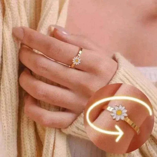 Gold fidget spinner ring with a daisy design, worn on a hand, highlighting the spinning feature.
