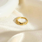 Snake-Shape Ring with 18K gold plating and zircon stones on a silk fabric background.
