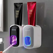 Automatic toothpaste dispenser with toothbrush holder mounted on a bathroom wall.