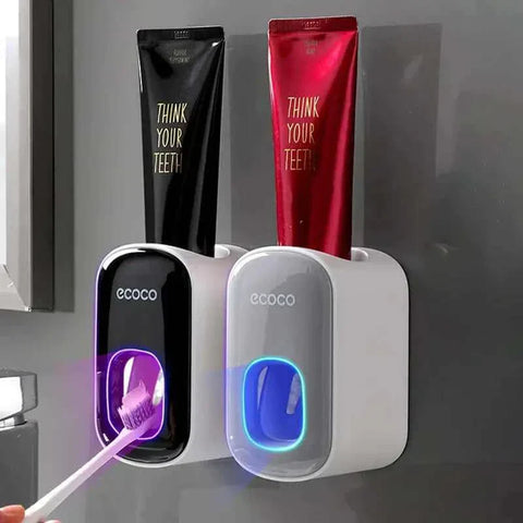 Automatic toothpaste dispenser with toothbrush holder mounted on a bathroom wall.