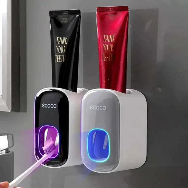Automatic toothpaste dispenser with toothbrush holder mounted on a bathroom wall.