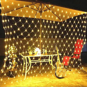 Net Mesh Solar Fairy Lights illuminating outdoor space with warm glow under an umbrella.